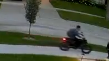 surveillance photo of young man on e-motor wearing black hat and backpack