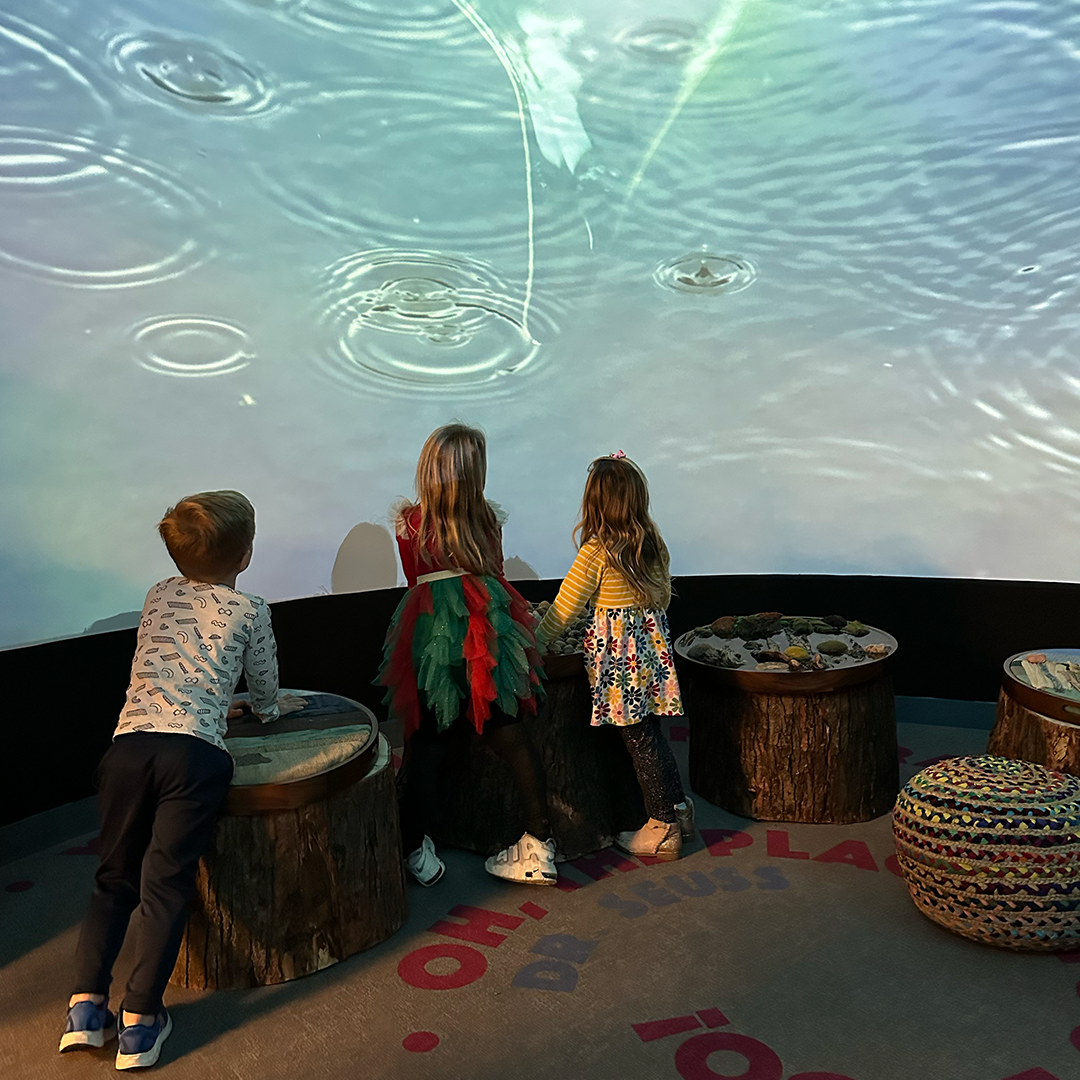 Children standing in the Wonder Room, featuring images of water on the wall and low lights