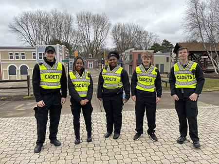 Five cadets in uniform and safety vests stand on the streets of Safety Town