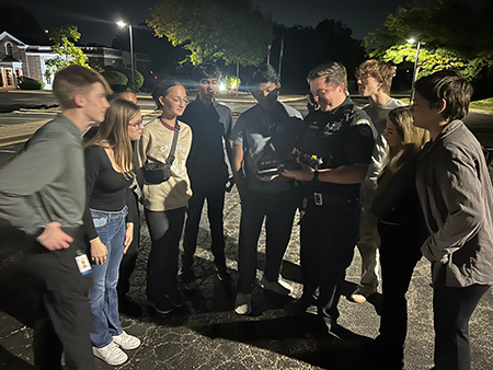 Cadets stand around an officer outdoors
