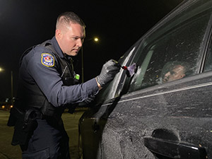 An officer dusts a car for fingerprints