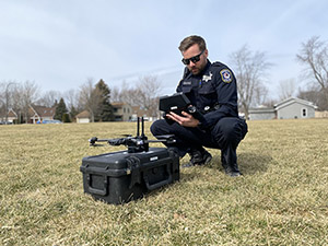 An officer crouches down, preparing to launch a drone